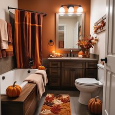 a bathroom decorated for fall with pumpkins and candles on the bathtub, toilet and sink