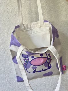 This adorable tote bag has designs on both sides. The front features lavender cow and the back has a plain cow pattern. It's perfect for everyday use! Item Details:♡Heavy Duty 12 oz canvas ♡Pocket with zipper for phone and key ♡Zipper on the top of the bag ♡Length 34 x Height 40 cm ♡Handle 3 x 56 cm ♡Digitally printed front and back designs How to care: Gentle wash with water, please avoid using harsh detergents and soaps. Trendy Cow Print Bags For Everyday Use, Casual Everyday Bag With Cow Print, Casual Cow Print Bags For Daily Use, Casual Purple Cotton Shoulder Bag, Purple Cotton Tote Shoulder Bag, Purple Cotton Shoulder Bag For Daily Use, Purple Cotton Bags For Daily Use, Purple Cotton Bag For Daily Use, Cow Pattern