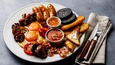 a white plate topped with lots of different types of food next to a fork and knife