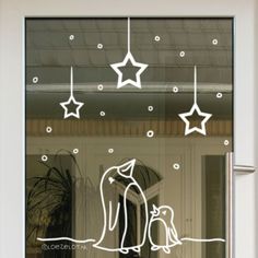 a glass door with a penguin and stars drawn on it's window sill