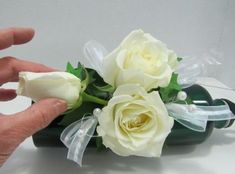 a person is placing flowers in a vase with ribbon around the stems and on top of it