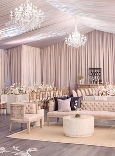 an elegant wedding reception setup with chandeliers and white drapes on the ceiling