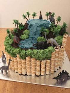 a birthday cake decorated with dinosaurs and trees