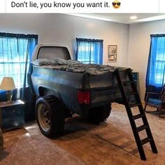 a truck bed sitting in the middle of a living room next to a window with blue curtains