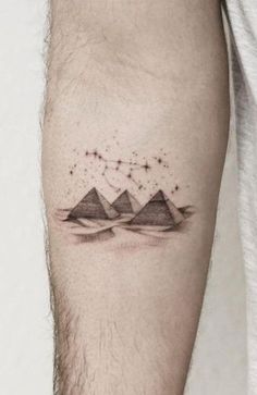 a man's arm with three mountains and stars tattoo on the left side of his arm