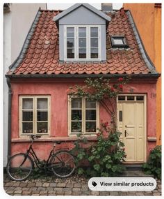 a bicycle parked in front of a house with flowers growing out of it's windows