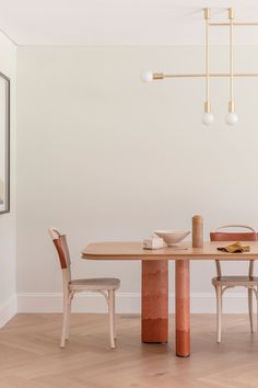 a dining room table with two chairs and a vase on the table next to it