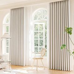 a living room filled with furniture and large windows covered in white curtained drapes