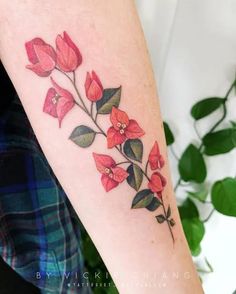 a woman's arm with red flowers and green leaves on the left inner arm