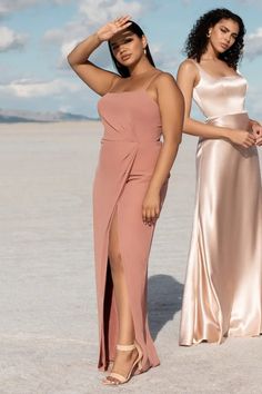 two women standing next to each other wearing dresses and one has her hand on her head