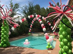 an outdoor pool decorated with balloons, streamers and candy canes in the shape of palm trees