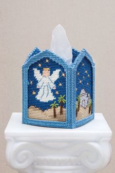 a blue tissue box with an angel on it's side and a palm tree in the background