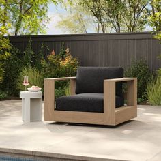 a chair sitting on top of a cement floor next to a swimming pool with trees in the background