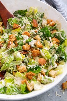 a salad with lettuce and croutons in a white bowl