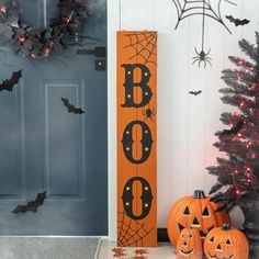 two pumpkins sitting in front of a door decorated for halloween with boo's on it