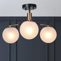 three lights hanging from the ceiling in a room with dark blue walls and wood paneling