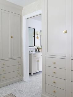 a white bathroom with gold handles and drawers