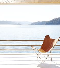 a brown chair sitting on top of a white floor next to a body of water