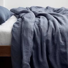 an unmade bed with blue sheets and pillows