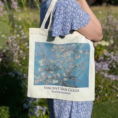 a woman holding a bag with an image of a blossoming tree