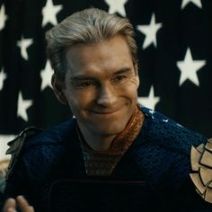 a close up of a person in front of an american flag with a smile on his face