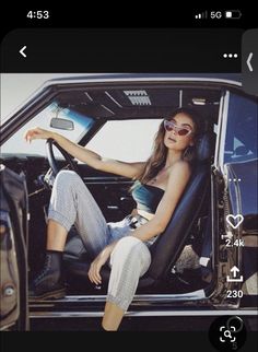 a woman sitting in the driver's seat of a car with her legs crossed