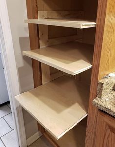 an empty pantry with wooden shelves and tile flooring