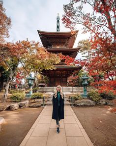 a woman standing in front of a tall pagoda