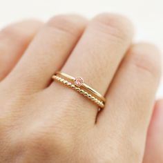 a woman's hand wearing a gold ring with two different colored stones on it