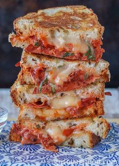 three grilled cheese sandwiches stacked on top of each other with tomato sauce and basil