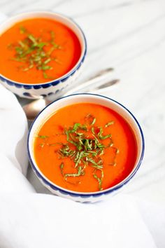 two bowls of tomato soup with garnish on top