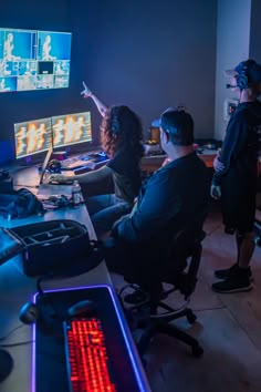 three people are playing video games on their computer screens in a dark room with neon lights