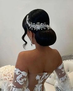 the back of a woman wearing a wedding dress with flowers in her hair and an elaborate headpiece