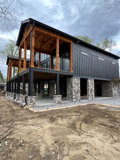 The contrast between the stonework, the siding color, the trim stain is Stunning Benjamin Moore Black Satin, Dark Barndominium, Benjamin Moore Black, Black Houses, Color Tips, River Cabin