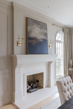 a living room with a fire place in the middle and a painting on the wall