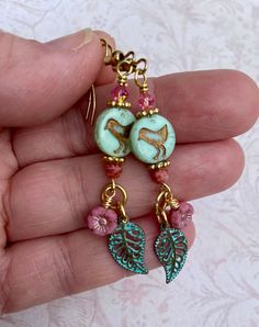 "I love the Spring! These earrings shout, \"Spring is here!\" The cute little chick beads are mint green with a gold wash. They are Czech glass beads. I added pretty green patina leaf charms and tiny pink Czech glass flowers. And to top it all off, I put pink Swarovski crystals on top. The earring hooks are 18k gold plated and are nickel free. Playful and fun yet so elegant, these earrings are a great spring accessory. Lever back hooks are available upon request. All of my earrings come on a han Czech Beads Jewelry, Earrings Bird, Czech Glass Jewelry, Stamped Earrings, Easter Earrings, Earrings Nature, Glass Bead Earrings, Spring Earrings, Bird Earrings