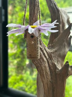 a birdhouse made out of wine corks with flowers hanging from it's sides