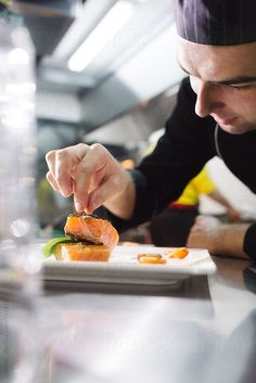 a chef is preparing food on a plate in the kitchen by jovan rijec for stocks