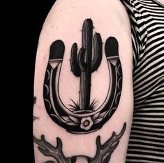 a black and white photo of a tattoo with an arrow, cactus, and antelope