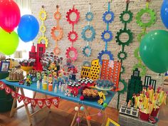 a birthday party with balloons, streamers and cake on a table in front of a brick wall