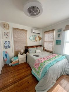 a bedroom with wood floors and white walls, has an air conditioner above the bed