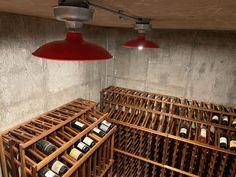 several wine bottles in wooden crates under two red light bulbs hanging from the ceiling above them