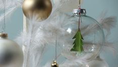 a christmas ornament hanging from a tree with white and gold ornaments around it