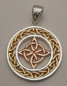 a gold and silver pendant with an intricate design on the center, surrounded by two intertwined