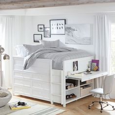 a white bed with drawers underneath it in a bedroom next to a desk and chair