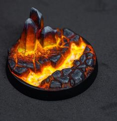 a close up of a fire with rocks in the middle and orange flames on it