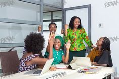 a group of women sitting around a table with laptops