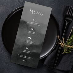 a black plate with a menu on it next to a fork and knife in the background