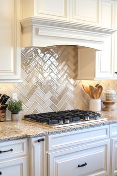 a kitchen with white cabinets and marble counter tops is pictured in this image, there are utensils on the stove