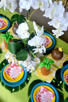 a table topped with plates and flowers on top of a green table cloth covered table